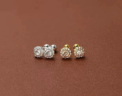 Three pairs of earrings in silver, gold, and rose gold on a brown surface.
